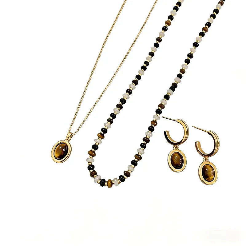 Tiger's eye gemstone jewelry collection with gold-plated chains and circular bead accents on a white background.