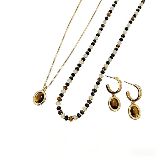 Tiger's eye gemstone jewelry collection with gold-plated chains and circular bead accents on a white background.