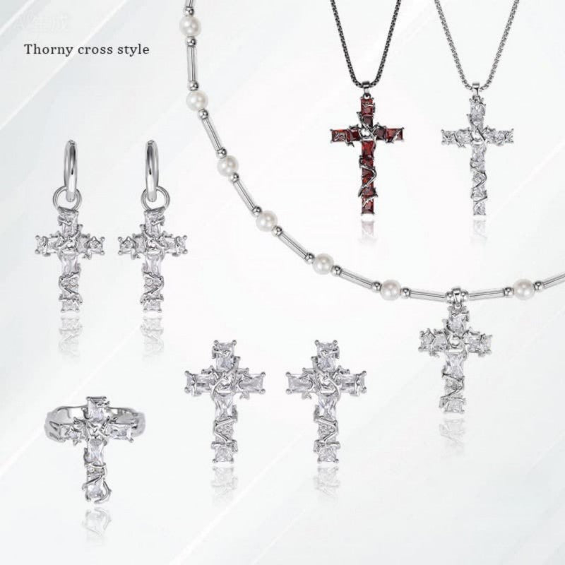 Mercury brand jewelry display featuring the Thorny Cross collection: silver crystal cross necklaces, red garnet thorn pendants, and matching gothic earrings on a minimalist background.
