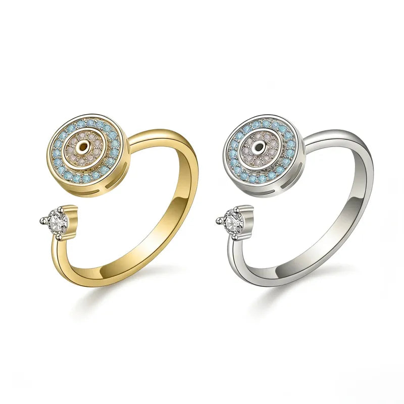 Two Mercury brand Evil Eye spinning fidget rings in gold and silver, featuring blue and white AAA cubic zirconia in a rotating celestial design, 24k gold plated jewelry for anxiety relief.