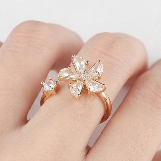 Close-up of a Mercury rose gold flower and star spinner ring on a finger, featuring sparkling AAA cubic zirconia on a minimalist white background.