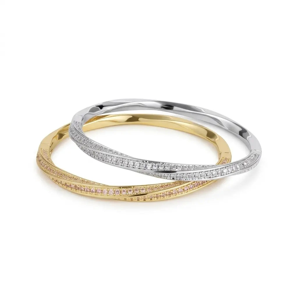 A product photograph of two interlocking, pave-set hinged bracelets, featuring one in 14k yellow gold set with natural fancy pink diamonds, and one in 14k white gold set with white diamonds, resting on a white surface against a white background.