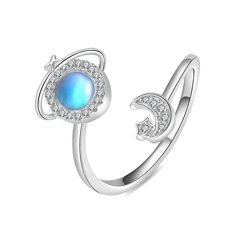Mercury brand stainless steel spinning ring featuring a rotating blue moonstone planet with a crystal halo and a matching crescent moon star.