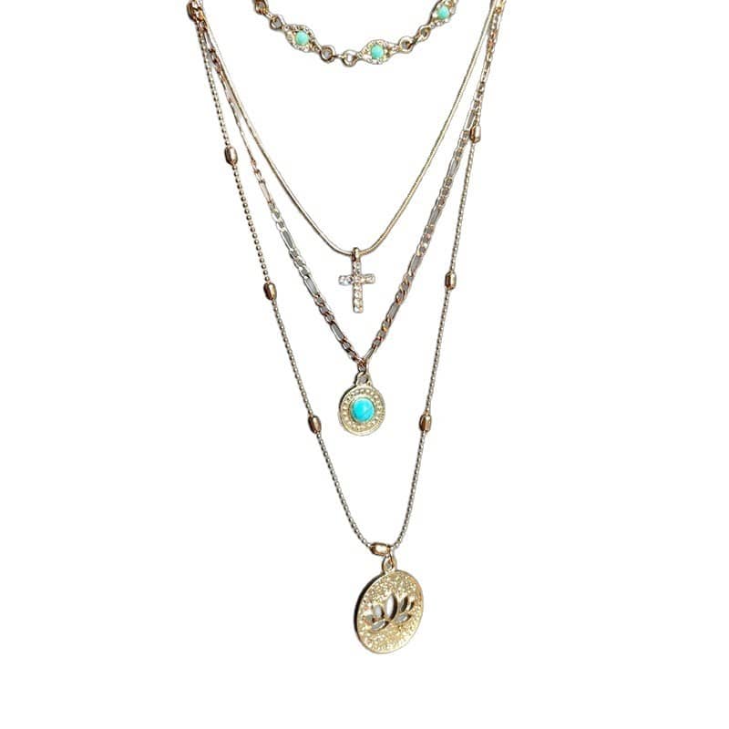 Mercury brand 18K gold plated stainless steel layered necklace featuring a turquoise choker, diamond-encrusted cross, and circular lotus flower pendant on a white background.