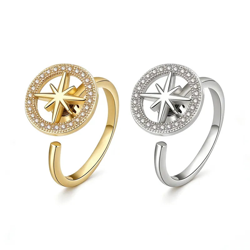 Two adjustable spinner rings in gold and silver finishes, featuring a crystal-encrusted halo and a central 3D eight-pointed star motif on a white background.
