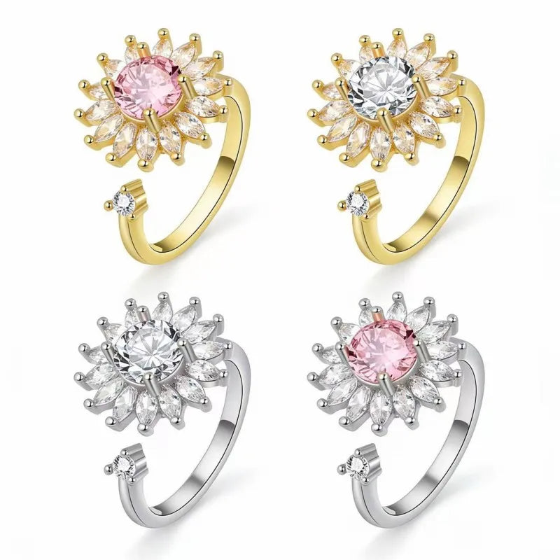 Four variations of a kinetic sunflower fidget ring for anxiety. The collection includes 18k gold-plated and 925 sterling silver finishes. Features include a rotatable flower head with sparkling pink and clear zirconias, designed as a "light luxury" spinning ring for stress relief.